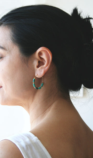 Model wearing turquoise beaded gold hoops earrings.