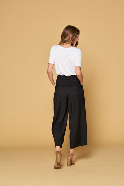 Back view of women's black button front pants with faux back pockets and fit to flare cut with wide legs.