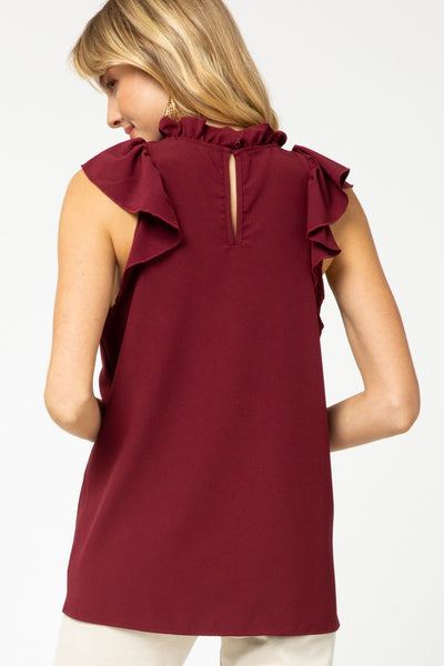 Back view of burgundy ruffle neck and sleeve top with keyhole closure.