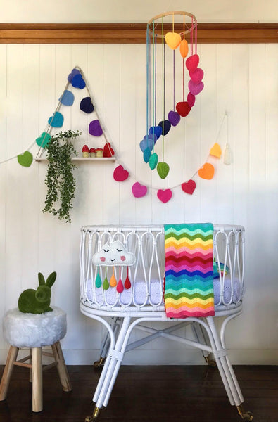Unique baby gifts. Rainbow heart mobile hanging over basinet.