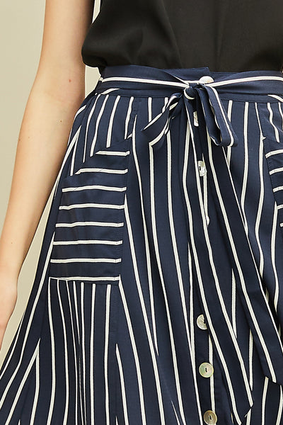 Close up of striped button up women's midi length skirt with pockets and elastic waist with tie detail.