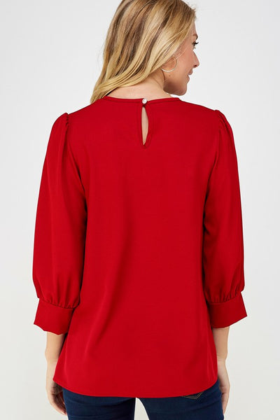 Back view of 3/4 sleeve top in red shown with keyhole opening at neck on back.