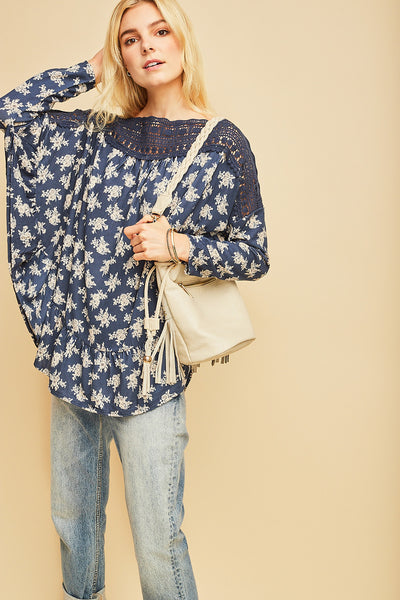 Long sleeve boho top in pretty blue color with white floral print with blue crochet detail along neck and shoulders.