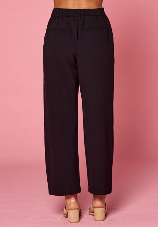 Back view of women&#39;s pleated black slacks with faux back pockets and back elastic waist.