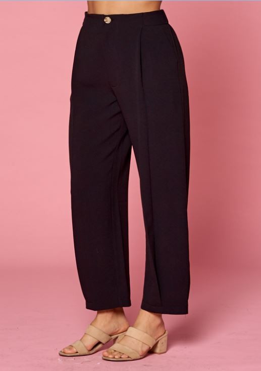 Side view of women&#39;s pleated black slacks with side pockets and front pleats with tacked pleat at hem.