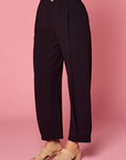 Side view of women's pleated black slacks with side pockets and front pleats with tacked pleat at hem.