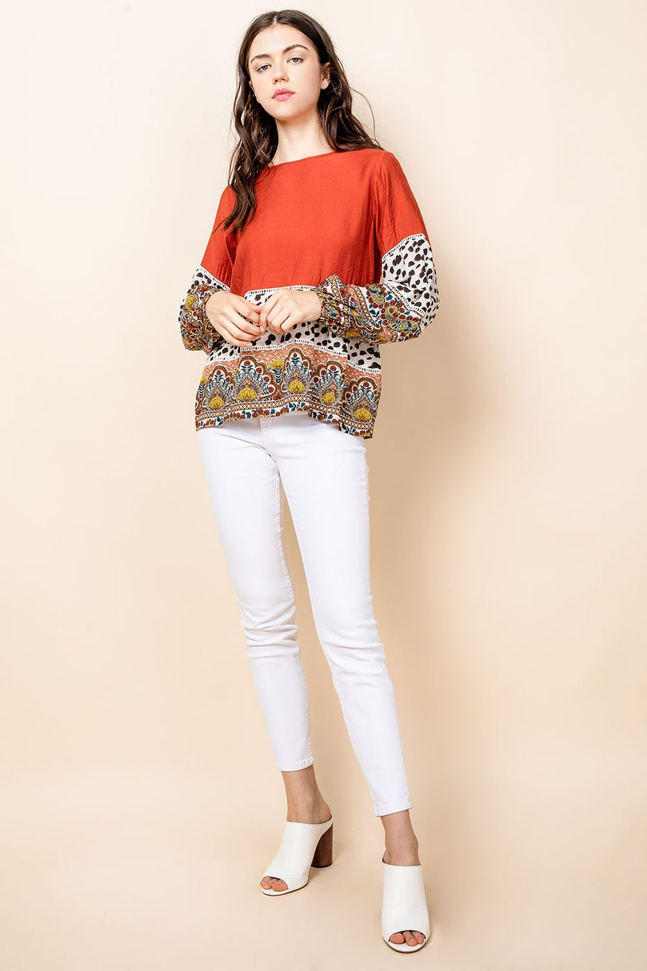 Woman&#39;s long sleeved animal and paisley top paired with white pants.