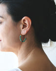 Model wearing turquoise beaded gold hoops earrings.