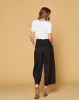 Back view of women's black button front pants with faux back pockets and fit to flare cut with wide legs.