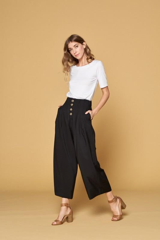 Women&#39;s black button front pants with four button closure and wide legs. Pockets. Culottes.