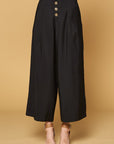 Close up of women's black button front pants in culotte cut with four button closure and wide legs.