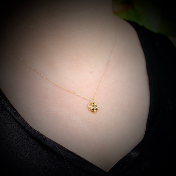 Model wearing delicate gold honeybee and hexagon necklace.