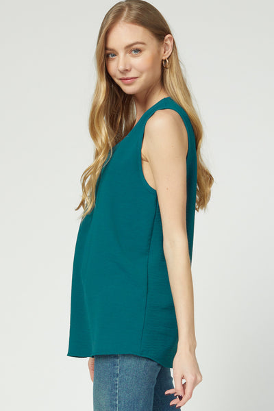 Side view of teal sleeveless blouse with good length for coverage.