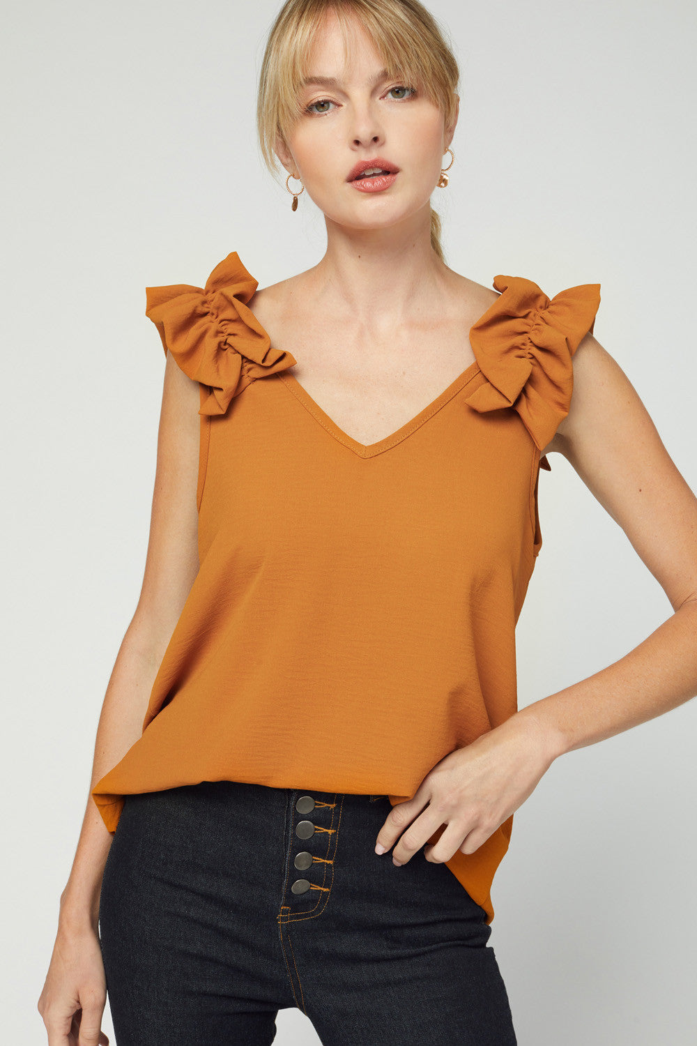 Fall fashion 2020 in camel colored v-neck sleeveless blouse with ruffle at strap.