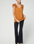 Full view of camel colored sleeveless v-neck top with ruffle at straps with good length for coverage paired with black pants and heels.