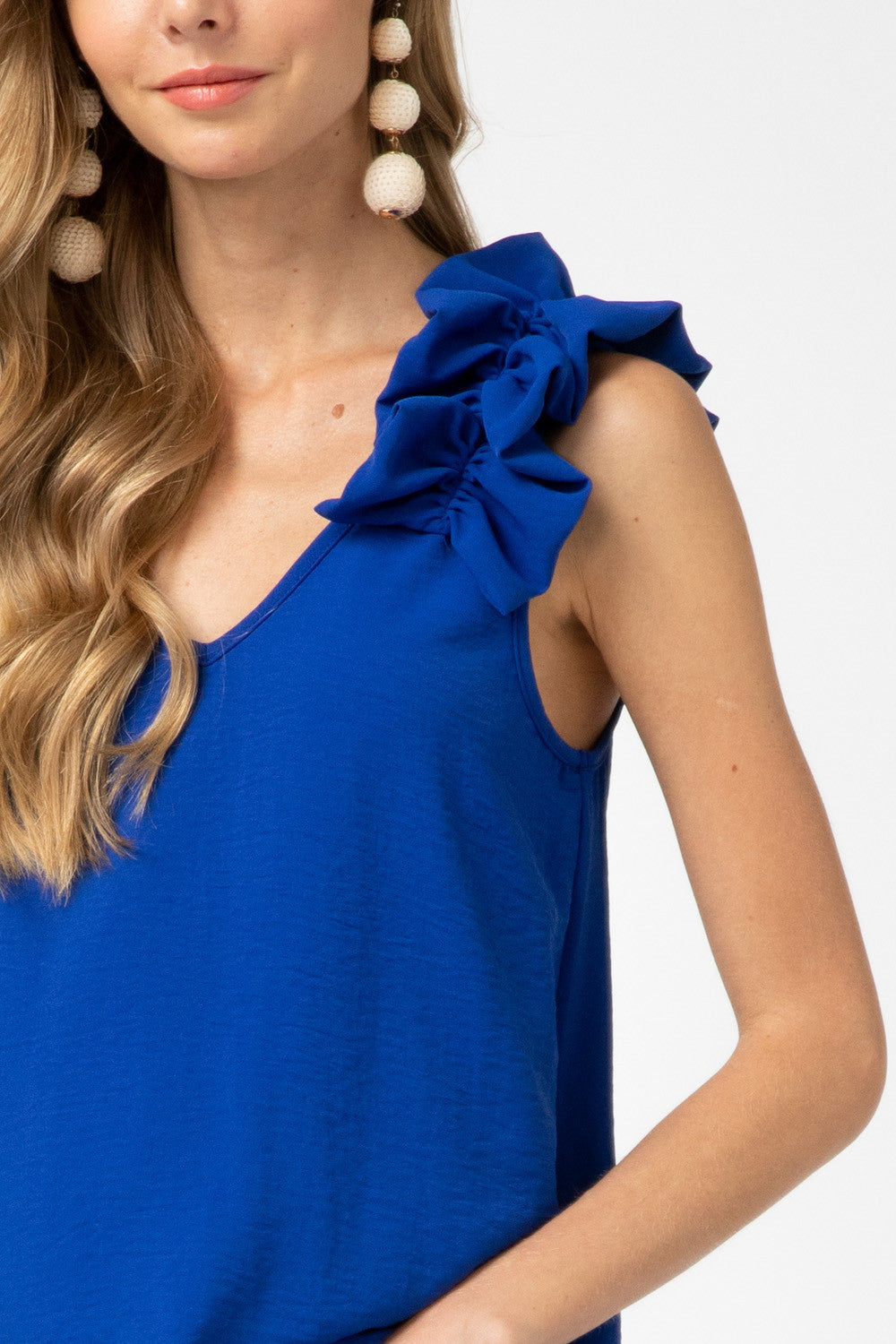 Close up view of ruffle detail at sleeveless strap on royal blue top.