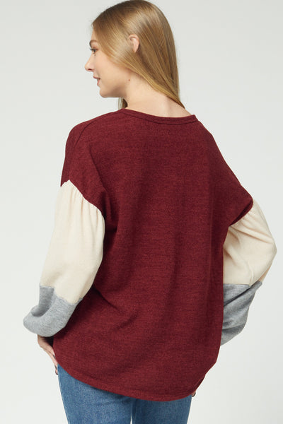 Back view of women's sweater in 2020 with solid bodice and color blocked puff sleeves with longer rounded hem for good coverage in back.