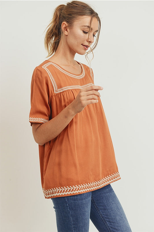 Women&#39;s boho style embroidered top in burnt orange camel color with off white embroidery.