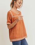 Women's boho style embroidered top in burnt orange camel color with off white embroidery.