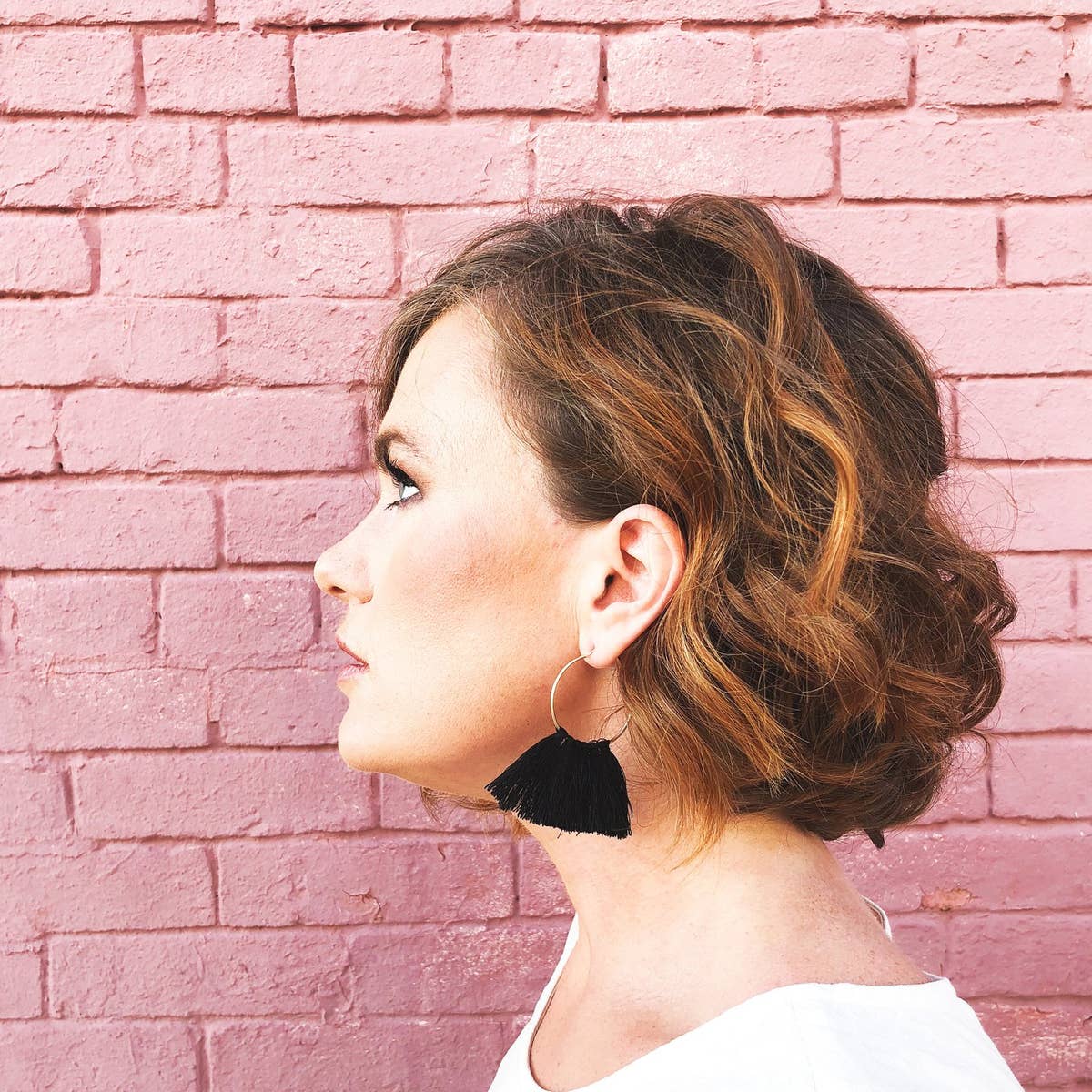 Black tassel hoop earrings on model.