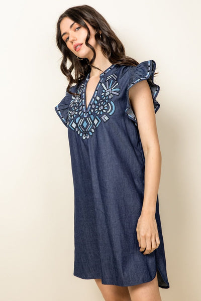 Side view of Woman's embroidered denim dress. Chambray with ruffle sleeves. V-neck.