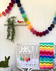 Giant pom pom rainbow garland in nursery.