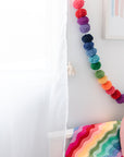 Little girl's room with rainbow pom pom garland hanging on wall.