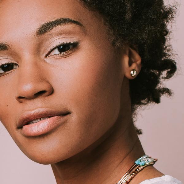 Woman modeling round stone studs dipped in gold.