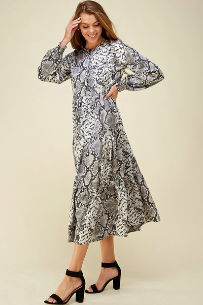Full skirt tiered maxi with button up bodice and long sleeves in snake print paired with black strappy heals.