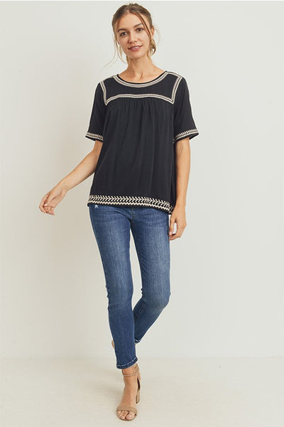 Full view of boho style embroidered top paired with denim.