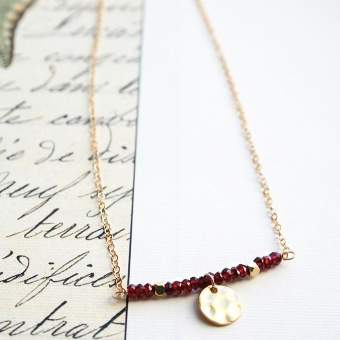 Faceted garnet bead necklace with gold hammered disc charm.