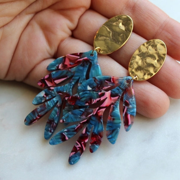 Hammered gold earrings with acrylic leaf pendants in blues and pinks.