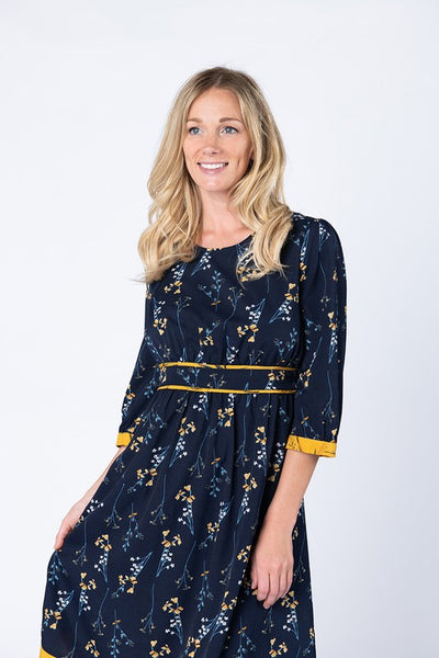 Close view of pretty navy 3/4 sleeve dress with pretty yellow flowers and yellow trimmed waist band with hidden elastic.