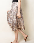 Side view of pleated snake skin midi skirt with brown flat sandals.