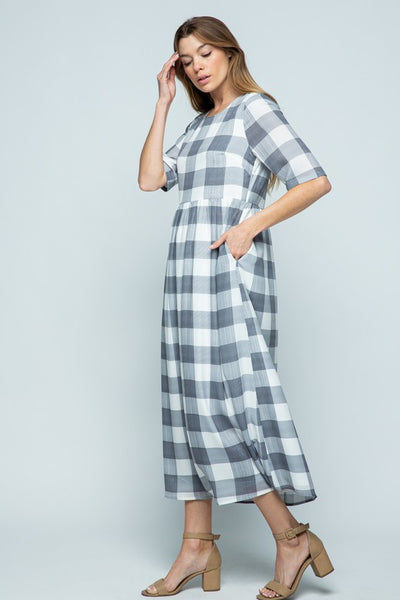 Side view of elbow length sleeve grey and white buffalo check midi dress with pockets.