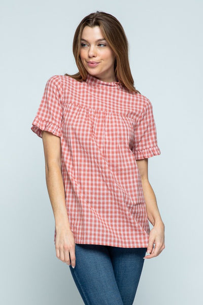 Cute woman's plaid top with mock neck and short ruffle sleeve paired with jeans.