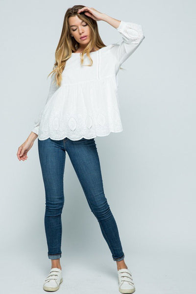 Full view of white embroidered 3/4 sleeve top paired with jeans and sneakers.