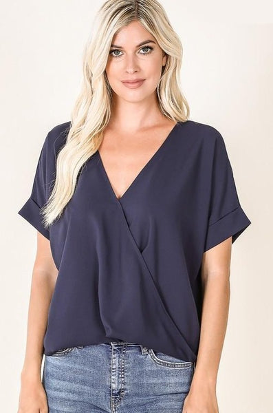 Navy blouse with short sleeves, v-neck, and faux front tuck and long back hem.