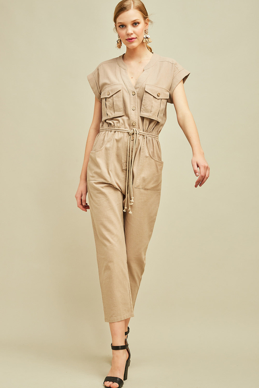 Women&#39;s jumpsuit with sleeves in khaki cargo cut with drawstring waist, cap sleeves, and button front. Straight leg.