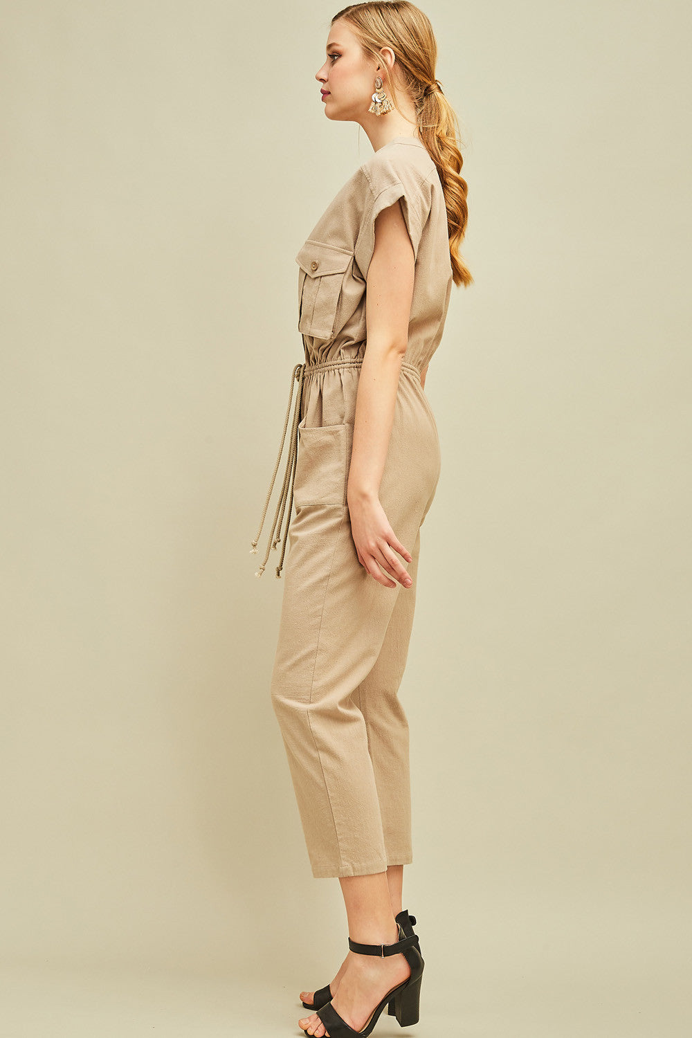 Side view of women&#39;s cargo jumpsuit in khaki with straight leg, check and side pockets, and drawstring waist.