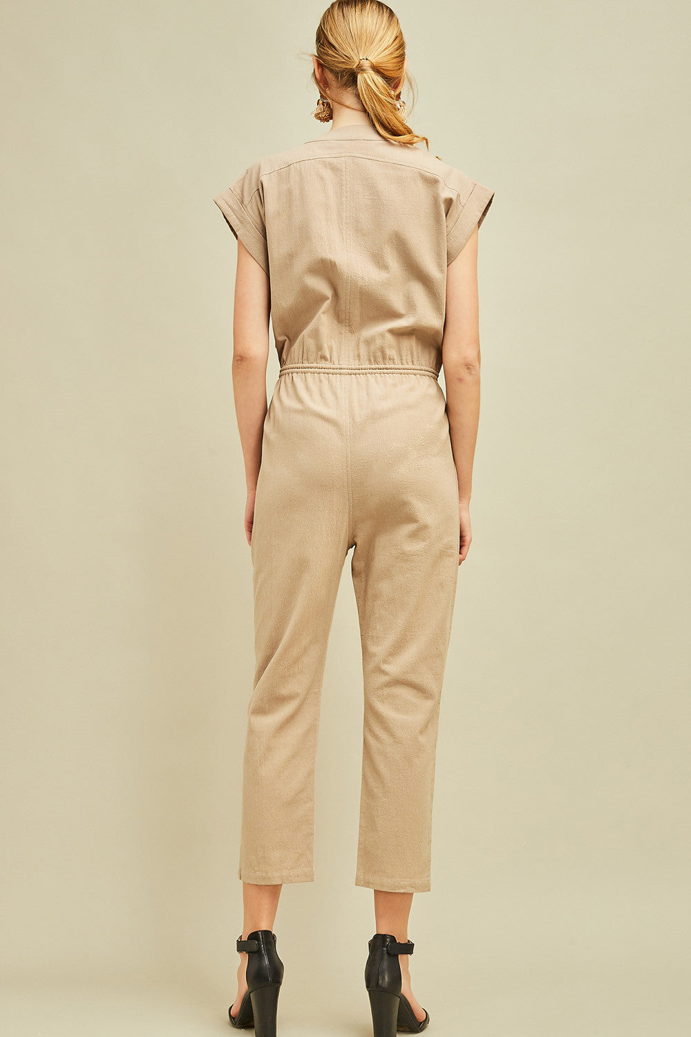 Back view of khaki colored cap sleeve straight leg drawstring waist jumpsuit.