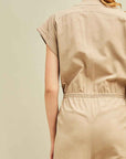 Close up view of back of khaki jumpsuit with cap sleeves and drawstring waist.