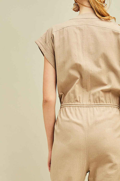 Close up view of back of khaki jumpsuit with cap sleeves and drawstring waist.