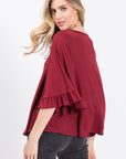 Back view of knit top in burgundy with full 3/4 flutter sleeves with ruffle.