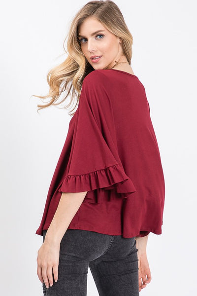 Back view of knit top in burgundy with full 3/4 flutter sleeves with ruffle.