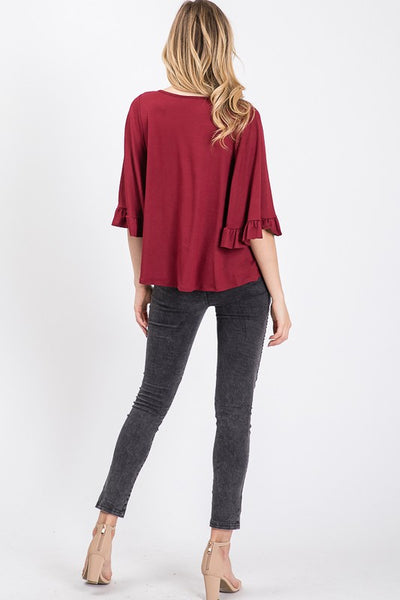 Full back view of burgundy top with ruffled 3/4 sleeve with good back coverage and length paired with black jeans and heels.