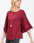 Round neck ruffle flutter sleeve top in burgundy dressed up with pretty gold jewelry.