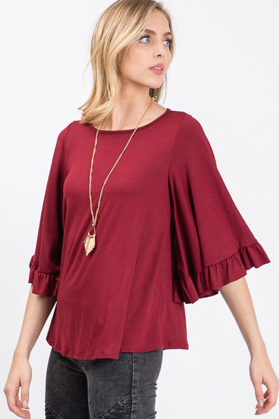 Round neck ruffle flutter sleeve top in burgundy dressed up with pretty gold jewelry.
