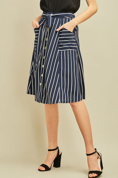 Button up navy women's midi skirt with white vertical stripes, pockets, tie detail over elastic waist.