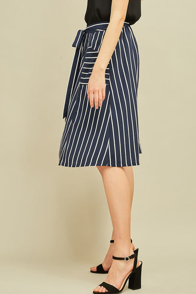 Side view of striped button up midi A-line skirt with pockets, elastic waist, and tie detail.